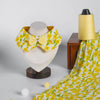 Pet collar with yellow flower print and bow tie, displayed with matching fabric and thread spool