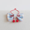 Blue and white plaid pet bow tie collar with red trim and pom poms on a light background
